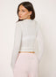 Woman wearing white sheer long sleeve t-shirt on a white background.
