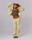 A model wearing a pale yellow hooded sweatshirt and matching sweatpants with  navy graphic prints, styled with an olive crop top, olive green cap, and gray sneakers against a light gray studio background.